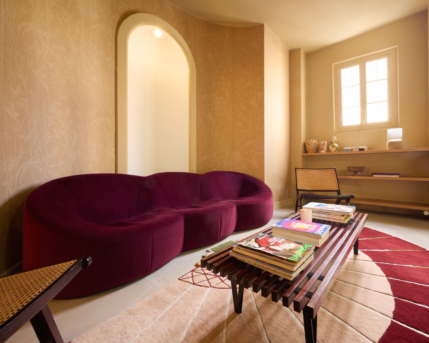 Salon d'attente avec canapé bordeaux et niche en arche