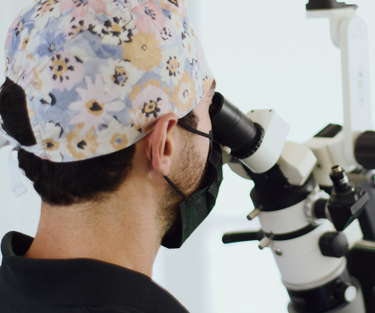 Praticien au microscope opératoire, en salle de soins du cabinet
