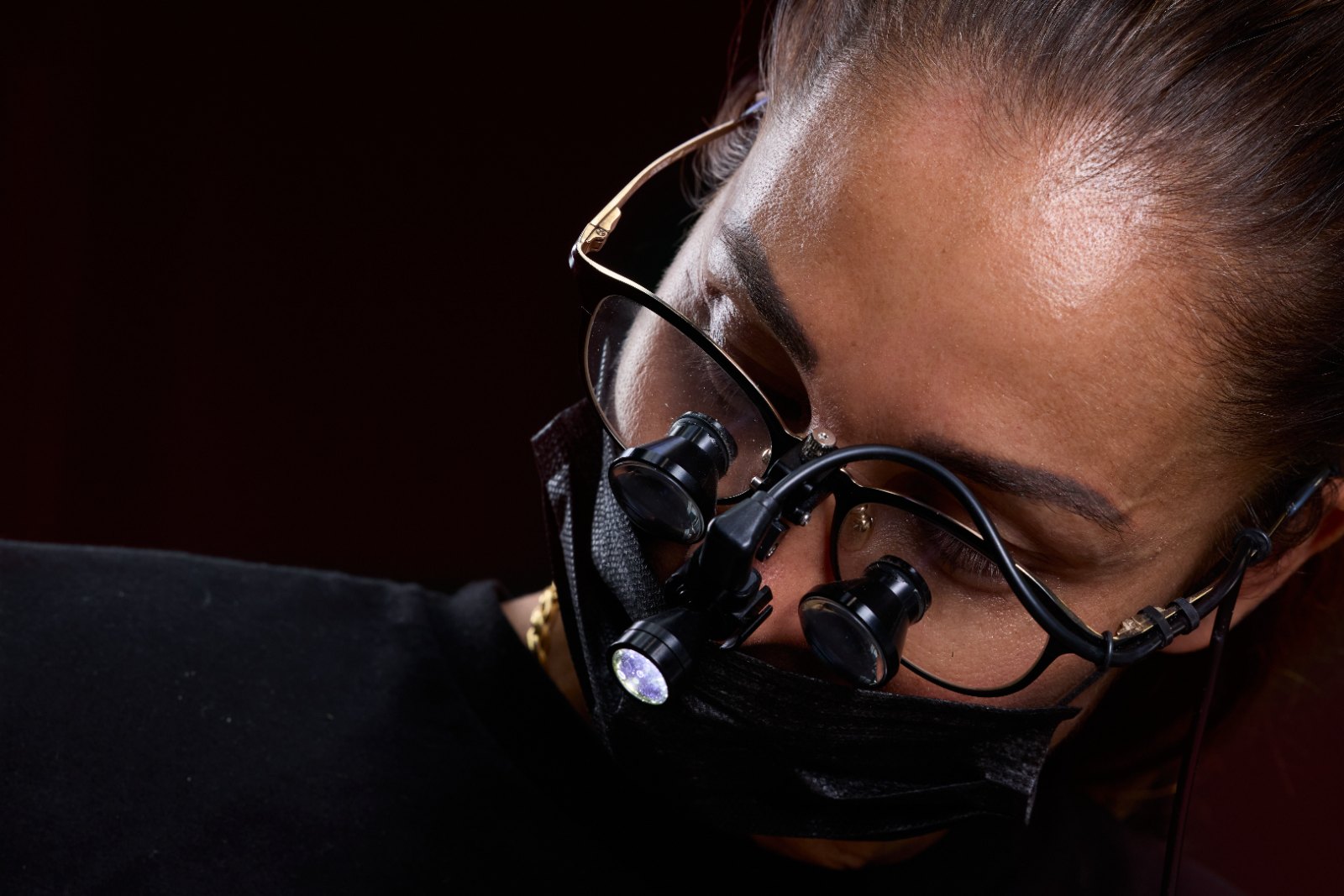 Praticien aux loupes binoculaires, penché sur un soin